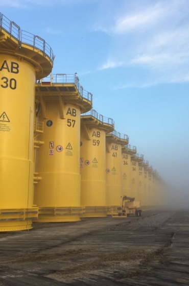 Yellow transition pieces for the Arkona offshore wind farm lined up at the quayside