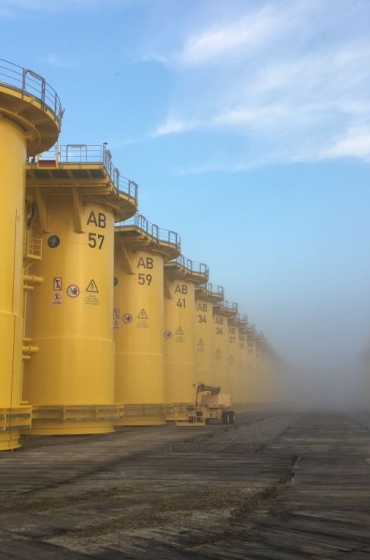 Yellow transition pieces for the Arkona offshore wind farm lined up at the quayside