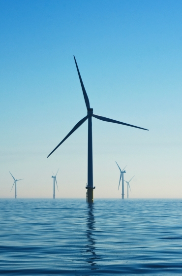 Offshore wind turbines in a calm sea under a clear blue sky